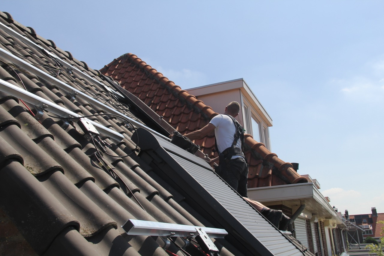 Monteur is zonnepanelen aan het leggen op het dak